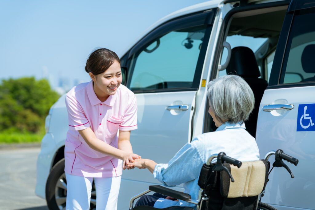 Caregiver assisting elderly woman into accessible van