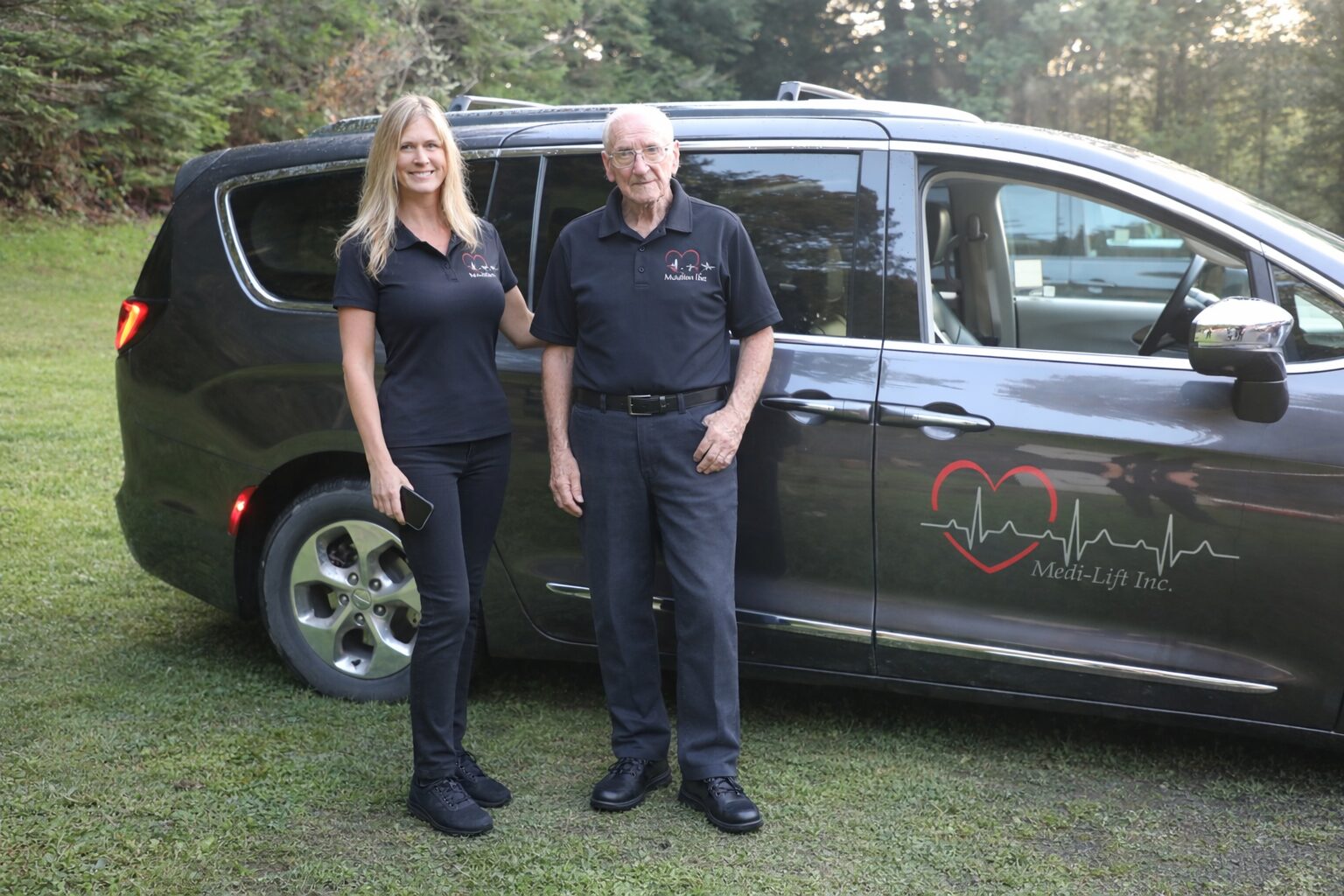 Two caregivers standing by medical transport van